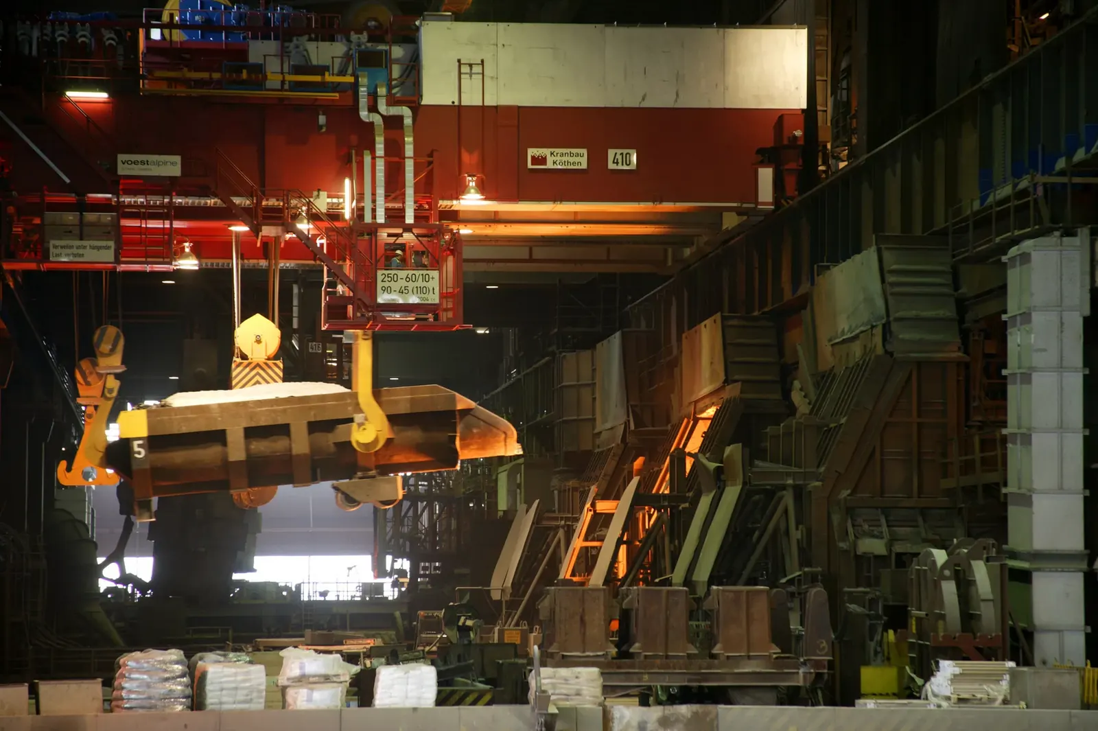 Overhead crane lifting a load in a steelworks hall