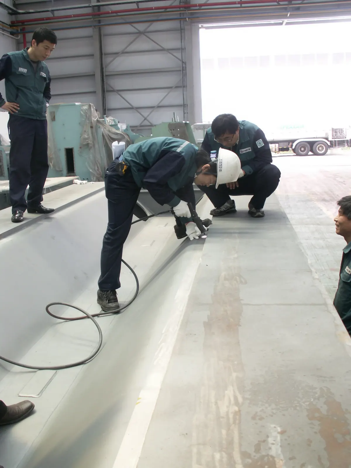 Engineers inspecting HFMI treatment of a long welded steel structure